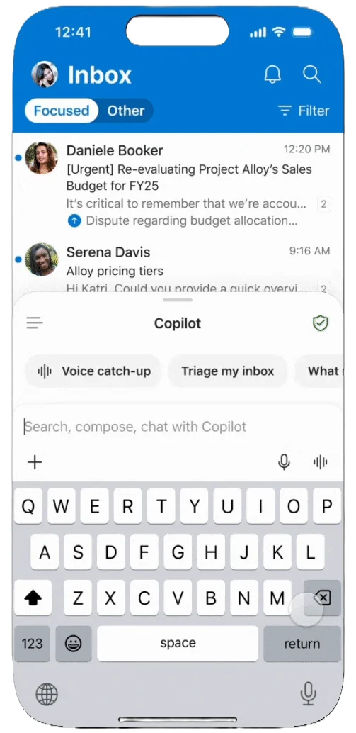 Outlook mobile inbox on iPhone with the Copilot bottom sheet open — quick action chips for 'Voice catch-up' and 'Triage my inbox' visible alongside a composer with the microphone and voice-conversation icons.